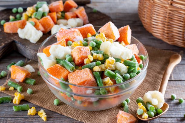 Mix of different frozen vegetables on wooden board on the table. Frozen food