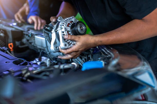 Mechanic is repairing and replacing a battery charger at car service center. Mechanic man holding alternator of the car in repair and maintenance garage.