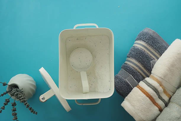 Clean towels are neatly arranged with detergent in a white container.