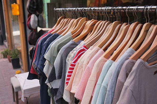 Shirts of various colors hang on a rack outside a trendy store.